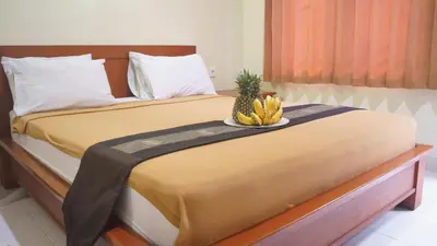 a bed with a bowl of bananas and a pineapple at Pondok Mirah in Kuta