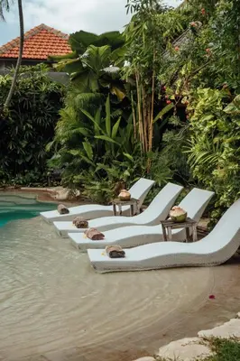 a row of lounge chairs next to a swimming pool at Villa Istimewa in Seminyak