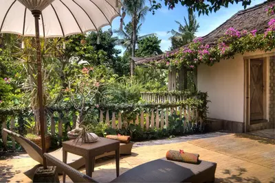 a patio with chairs and an umbrella next to a house at Villa Istimewa in Seminyak