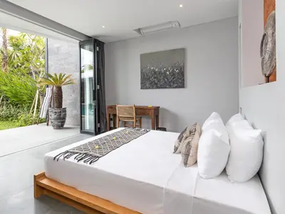 a white bedroom with a bed and a balcony at Villa Castil di Udara by Villa Finder in Kerobokan