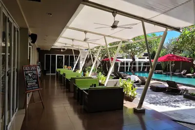 a row of tables with umbrellas next to a pool at The Kana Kuta Hotel in Kuta