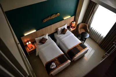a hotel room with two beds and a window at The Kana Kuta Hotel in Kuta