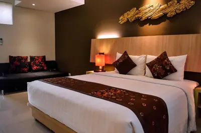 a hotel room with a large bed and a couch at The Kana Kuta Hotel in Kuta