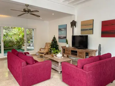 a living room with two red chairs and a tv at Beach House Canggu - 150m Berawa beach in Canggu