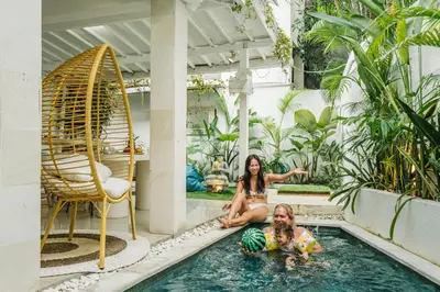 two girls are sitting in a swimming pool at Mara Villa, Garden & Pool, 2 min to Seminyak Beach in Seminyak