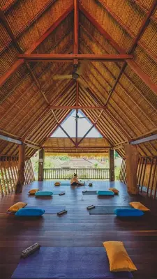 a large room with a large wooden ceiling with blue pillows at Amnaya Resort Nusa Dua in Nusa Dua