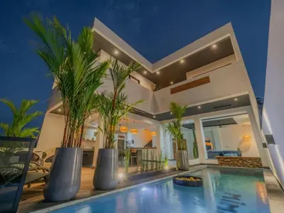 a house with a swimming pool with palm trees in it at Villa Mimpi Bali in Jimbaran