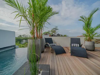 a deck with chairs and plants next to the water at Villa Mimpi Bali in Jimbaran