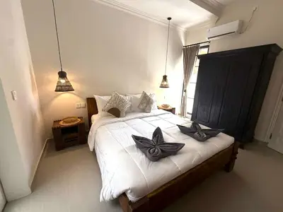 a bedroom with a white bed with black bows on it at de CINTA Villa - KUTA - 6 bedrooms - Heart of Kuta in Kuta