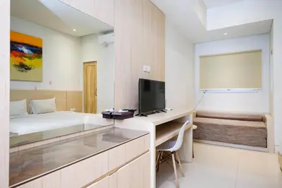 a bedroom with a bed and a desk with a tv at Lega Legi Town House Seminyak by The Lavana in Seminyak