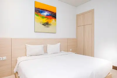 a bedroom with a white bed and a painting on the wall at Lega Legi Town House Seminyak by The Lavana in Seminyak