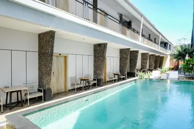 a large swimming pool in a building with tables and chairs at Lega Legi Town House Seminyak by The Lavana in Seminyak