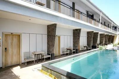 a swimming pool in a building with tables and chairs at Lega Legi Town House Seminyak by The Lavana in Seminyak