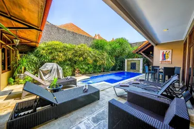 an outdoor patio with chairs and a swimming pool at Villa SANKET - KUTA - 6 bedrooms - 6 bathrooms - Great Location in Kuta