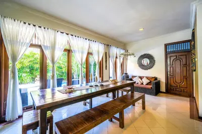a dining room with a long table and a couch at Villa SANKET - KUTA - 6 bedrooms - 6 bathrooms - Great Location in Kuta
