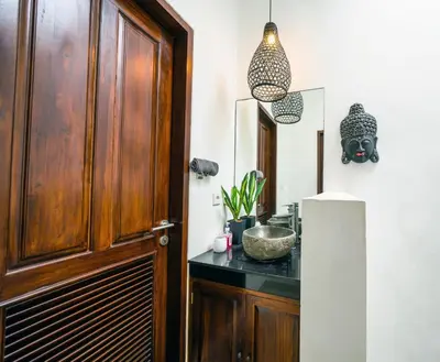 a bathroom with a wooden door and a sink at OASIS 66 Villa - Heart of Legian/Seminyak - Double Six in Seminyak