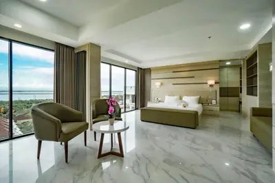 a bedroom with a bed and a couch and a chair at Sunrise Aventus Hotel Nusa Dua in Nusa Dua