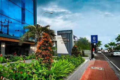 a street with a building with a sign and plants at Sunrise Aventus Hotel Nusa Dua in Nusa Dua