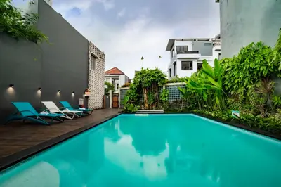 a swimming pool in the backyard of a house with blue chairs at Sunrise Aventus Hotel Nusa Dua in Nusa Dua