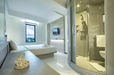 a white bathroom with a bed and a shower at Sunrise Aventus Hotel Nusa Dua in Nusa Dua