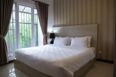 a bedroom with a large white bed and a window at Sunrise Aventus Hotel Nusa Dua in Nusa Dua