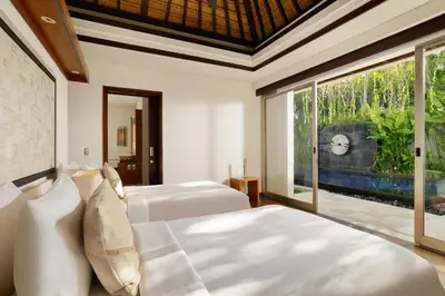a bedroom with two beds and a large window at Jimbaran Bay Villas by Nakula in Jimbaran