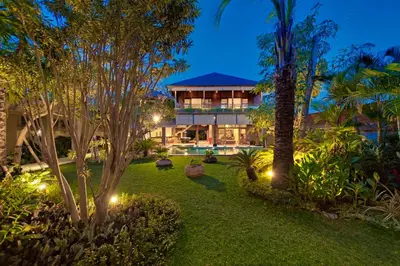 an exterior view of a resort with palm trees and lights at Villa Kinaree Estate in Seminyak