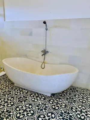 a bath tub with a shower in a bathroom at Villa Biru - 500m Batubelig beach in Canggu