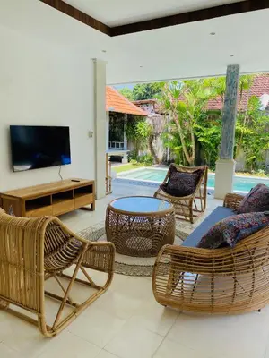 a living room with wicker furniture and a tv at Villa Biru - 500m Batubelig beach in Canggu