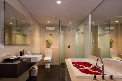 a bathroom with a tub and a toilet and a sink at J4 Hotels Legian in Legian
