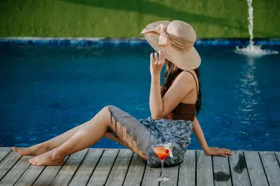 a woman sitting on a dock next to a pool at J4 Hotels Legian in Legian