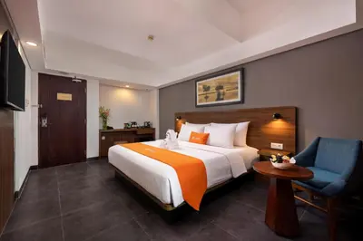 a hotel room with a large bed and a blue chair at J4 Hotels Legian in Legian