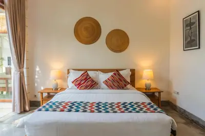 a bedroom with a bed with two lamps on the wall at Canggu Escape Villa By Island Escape in Canggu