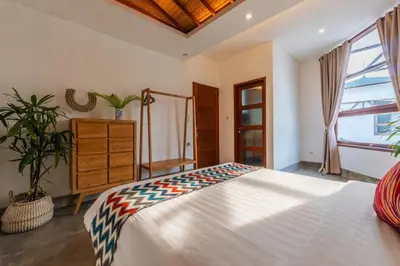 a bedroom with a large white bed and a window at Canggu Escape Villa By Island Escape in Canggu