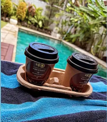 two cups of coffee on a tray next to a pool at Luka Villas - Luxury 2 Bedroom Private Pool Villa in Seminyak