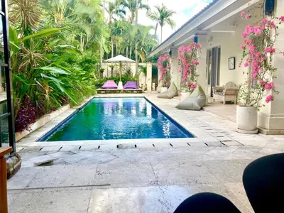 a swimming pool in a backyard with pink flowers at villa LA PLAYA in Seminyak