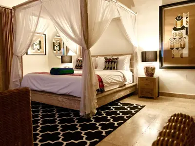 a bedroom with a canopy bed with a black and white rug at villa LA PLAYA in Seminyak