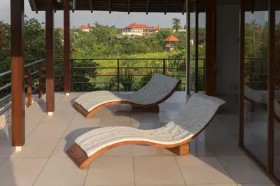 two chairs sitting on a balcony with a view of a field at Villa Kavya - 8-minute walk from Berawa Beach in Canggu
