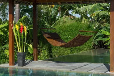 a hammock sitting next to a swimming pool at Villa Kavya - 8-minute walk from Berawa Beach in Canggu