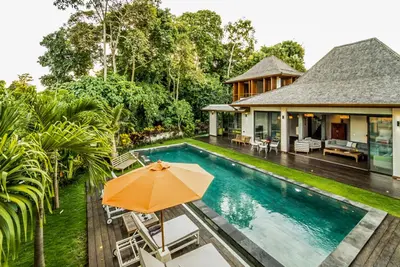 an orange umbrella sitting next to a house with a swimming pool at PROMO Large Astonishing 5 BR Luxury Private Villa in Canggu