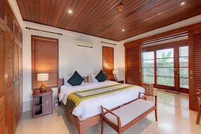a bedroom with a large white bed and wooden ceilings at Villa Dorado - Steps from Jimbaran Beach in Jimbaran