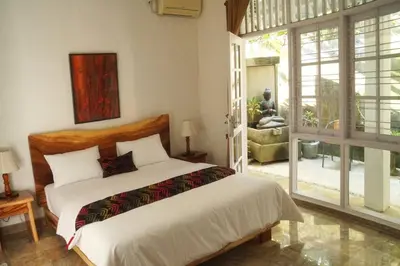 a bedroom with a bed and a large window at Miracle Villa Sanur in Sanur