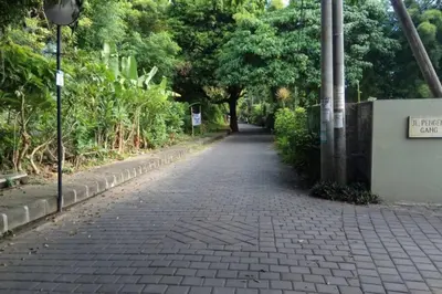 a brick road with trees and a sign on a wall at Miracle Villa Sanur in Sanur