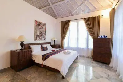 a bedroom with a large bed and a window at Miracle Villa Sanur in Sanur