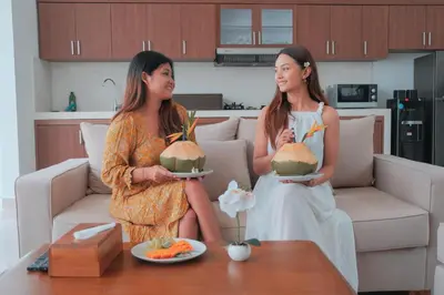 two women standing in a living room holding a watermelon at Villa Akmali Seminyak Basangkasa- 2 Bedrooms in Seminyak