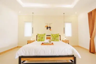 a bedroom with a large white bed and two windows at Villa Orked 3 with family room Seminyak in Seminyak