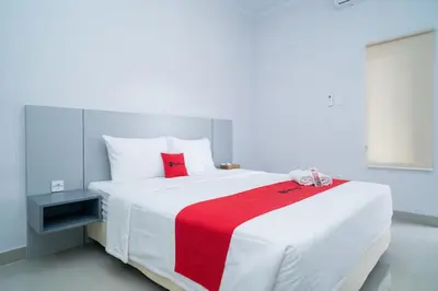 a bedroom with a large white bed with a red blanket at RedDoorz @ Jalan Gunung Talang Mahendradatta in Kerobokan