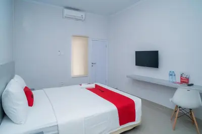 a white bedroom with a red blanket on a bed at RedDoorz @ Jalan Gunung Talang Mahendradatta in Kerobokan