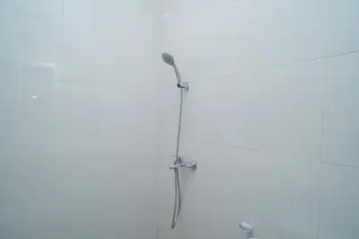a shower with a shower head in a bathroom at RedDoorz @ Jalan Gunung Talang Mahendradatta in Kerobokan