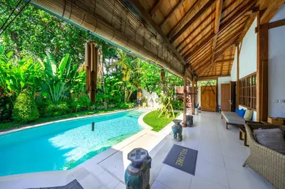 an indoor swimming pool with a patio and a house at Villa Kainara Seminyak by RPM in Seminyak
